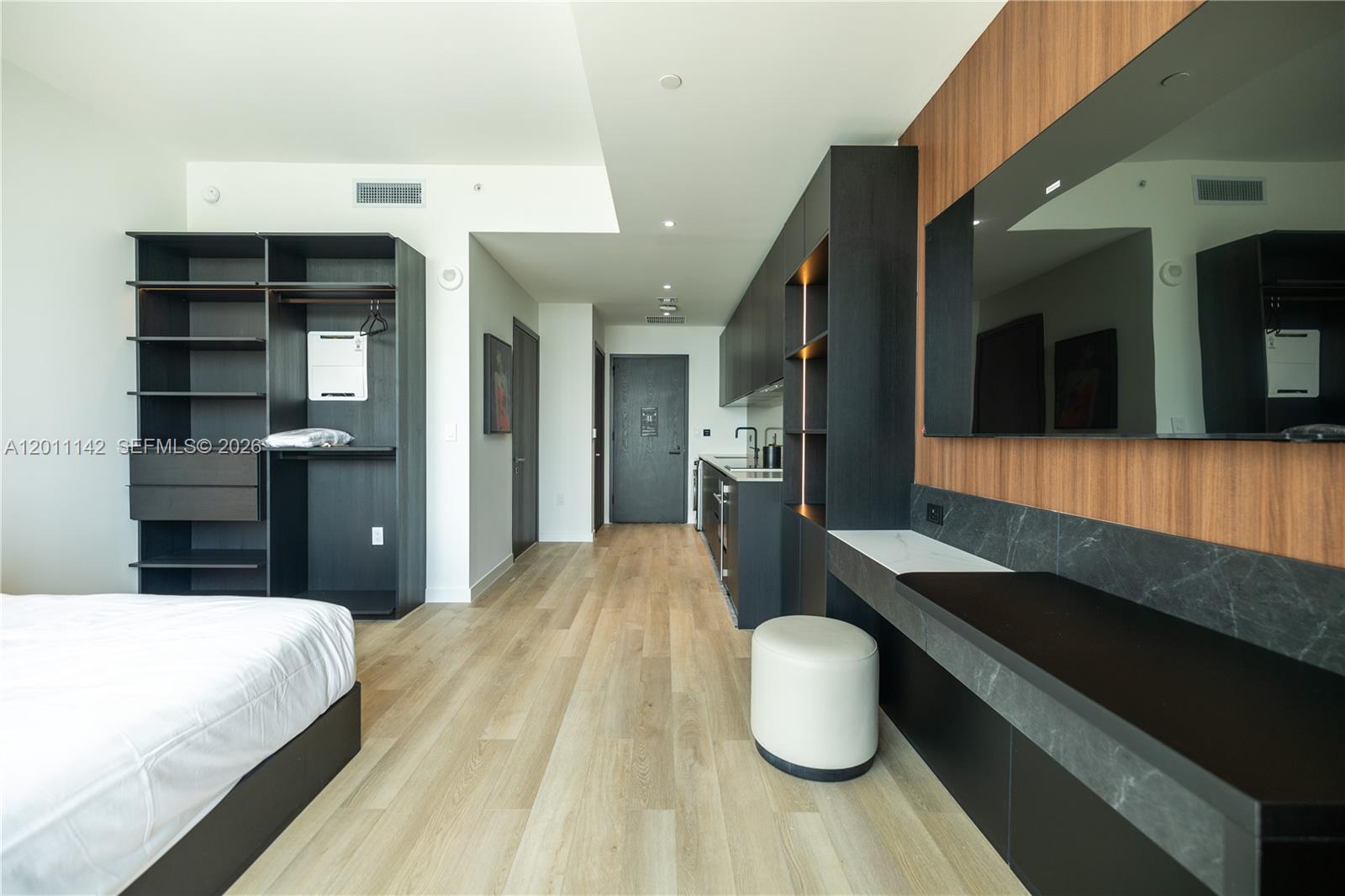A studio apartment features a kitchenette, built-in shelving, a desk, and wood-look flooring — 20 NE 11th st # 5306, Miami FL 33132, MIAMI, FL