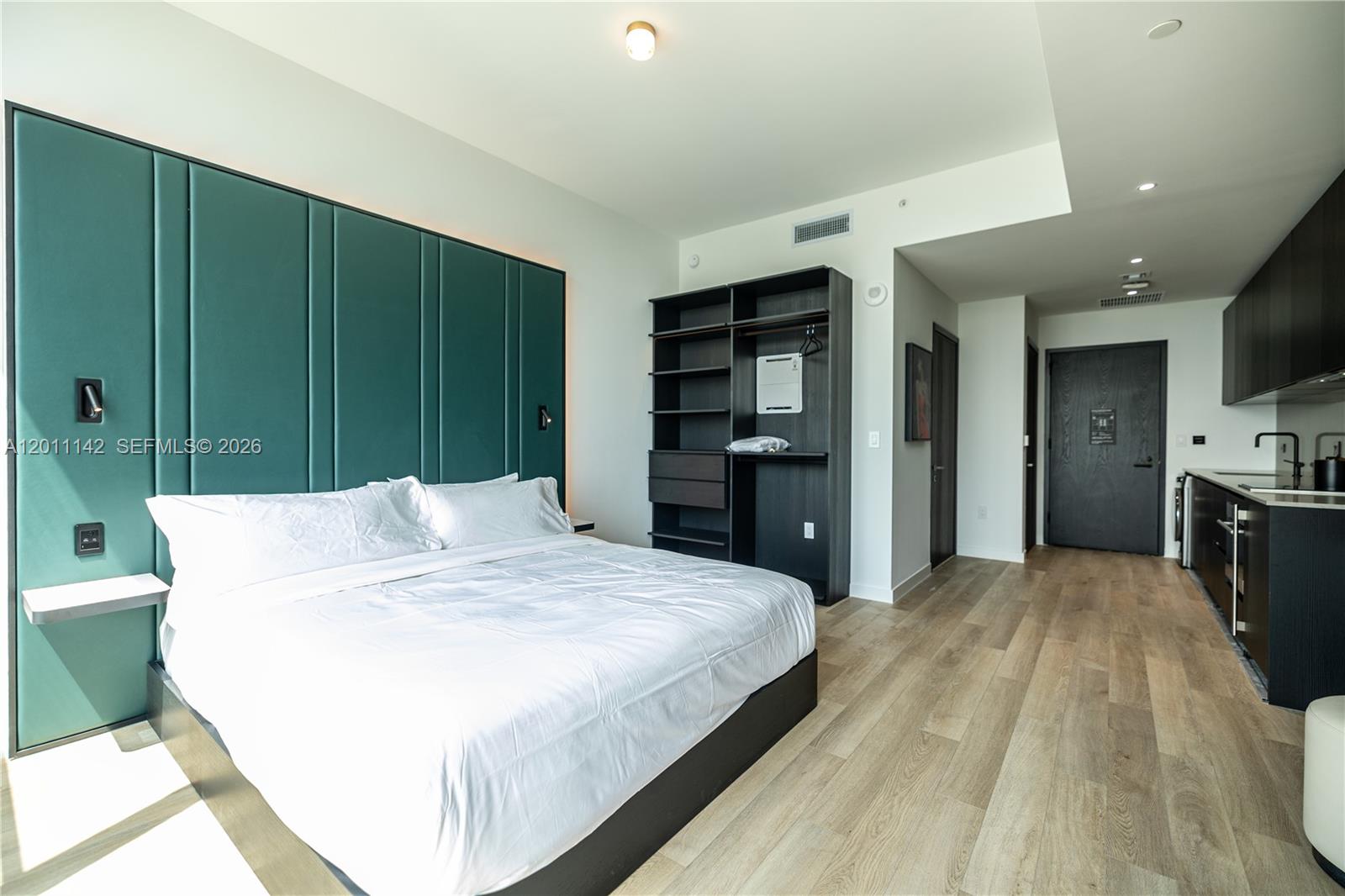 A studio apartment features a bed with a teal headboard, open shelving, and a kitchenette — 20 NE 11th st # 5306, Miami FL 33132, MIAMI, FL