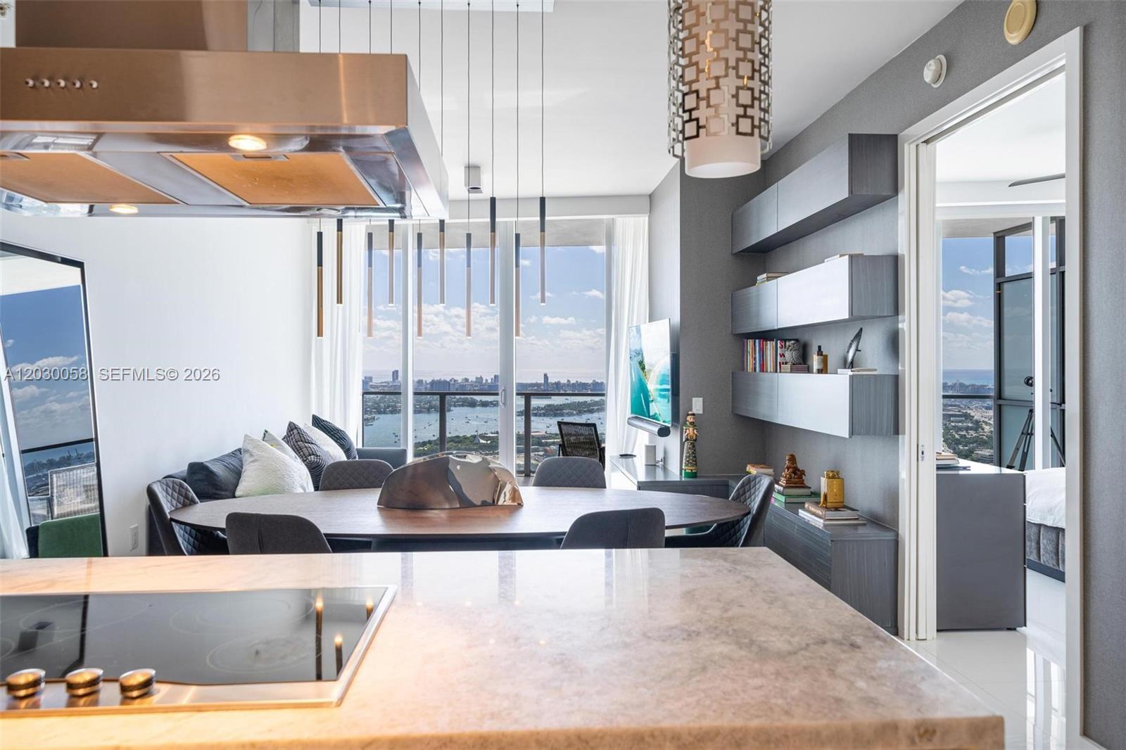 A modern kitchen and dining area features a marble island, pendant lights, and water views — 1100 Biscayne Blvd # 5203, Miami FL 33132, MIAMI, FL