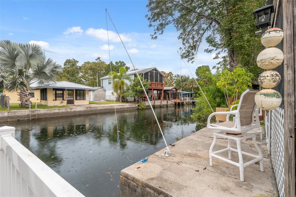A concrete dock overlooks a narrow canal with houses on the opposite bank — 5527 DARLENE STREET, WEEKI WACHEE, FL