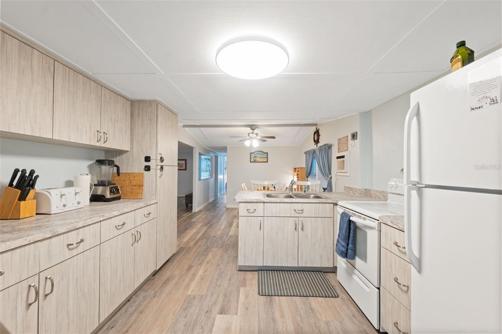 A kitchen features light wood-grain cabinets, white appliances, and wood-look flooring — 5527 DARLENE STREET, WEEKI WACHEE, FL