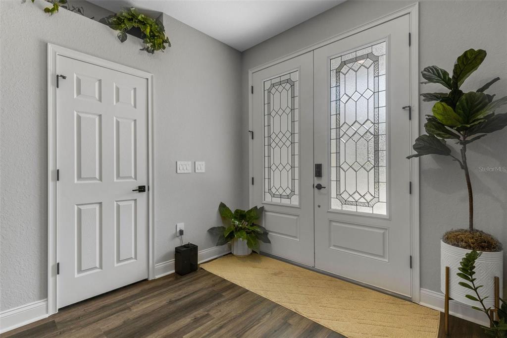 An entryway features a white double front door with glass panels, wood flooring, and plants — 2980 KEENS GROVE WAY, LAKELAND, FL