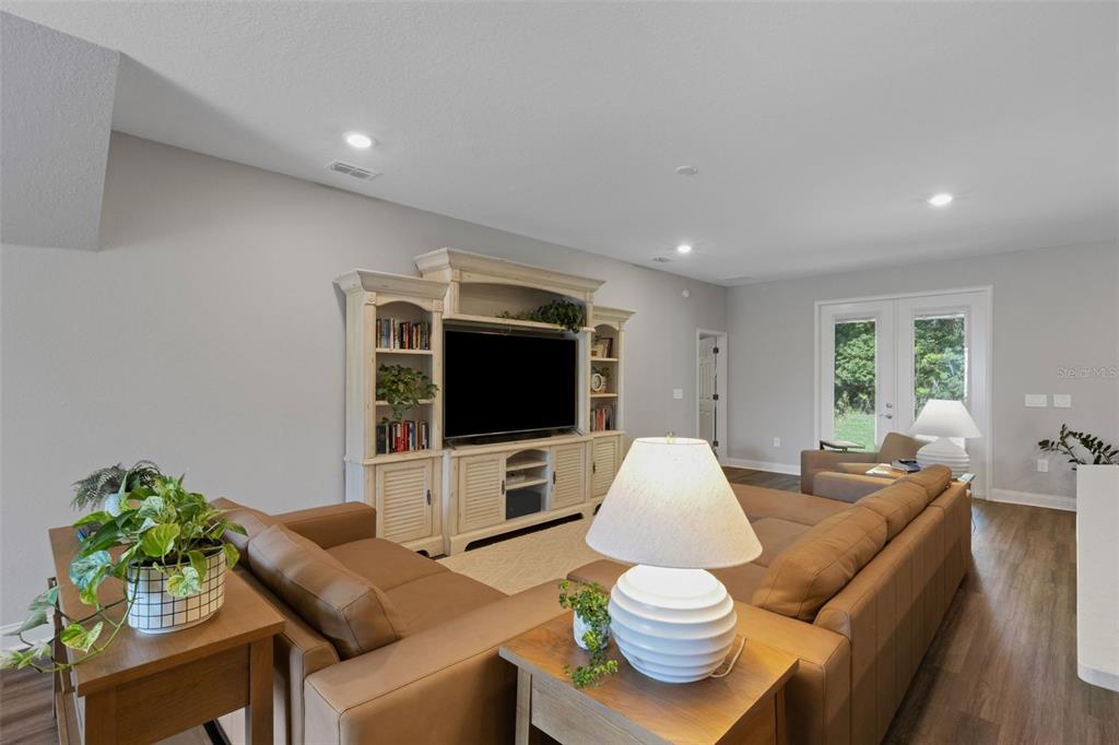A living room features a large entertainment center, brown sectional sofa, and wood-look flooring — 2980 KEENS GROVE WAY, LAKELAND, FL
