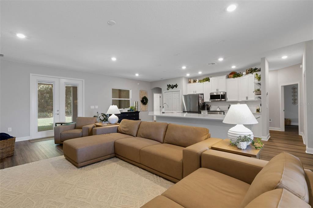 A spacious open-concept living room features a large brown sectional sofa and a modern kitchen — 2980 KEENS GROVE WAY, LAKELAND, FL