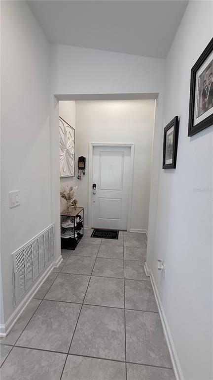 A tiled entryway features a white front door, a shoe rack, and framed wall art — 225 LAWSON AVENUE, HAINES CITY, FL