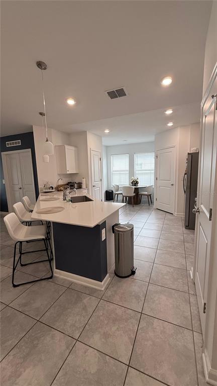 A kitchen with a white quartz island, bar seating, and tile flooring leads to a dining area — 225 LAWSON AVENUE, HAINES CITY, FL