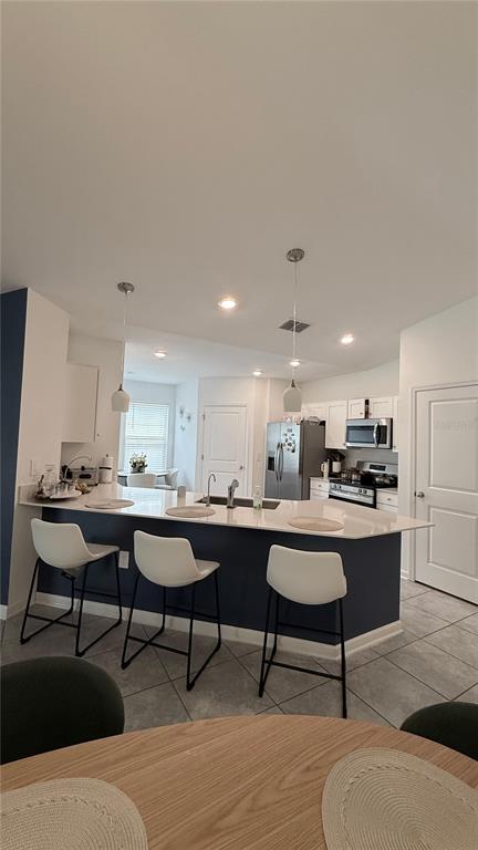 A kitchen features a dark blue island with white bar stools and stainless steel appliances — 225 LAWSON AVENUE, HAINES CITY, FL