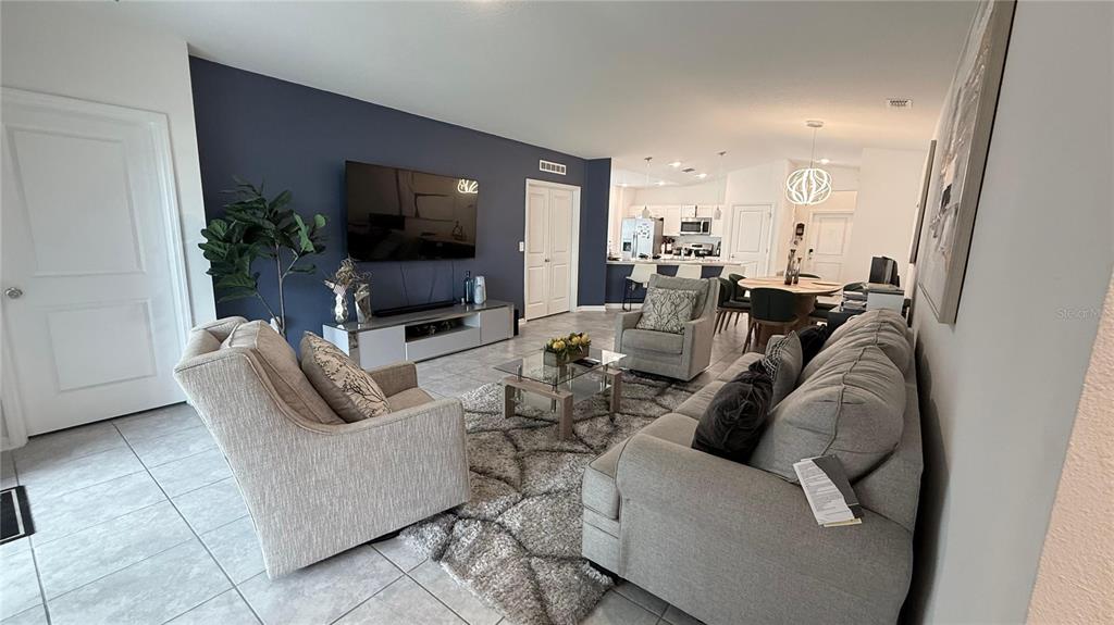 A living room with a dark blue accent wall, gray furniture, and an open kitchen — 225 LAWSON AVENUE, HAINES CITY, FL