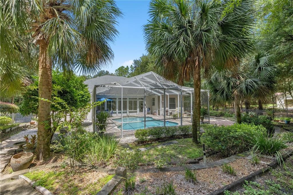 A screened-in swimming pool with a paver deck and a blue patio umbrella — 18293 SW 75TH LOOP, DUNNELLON, FL