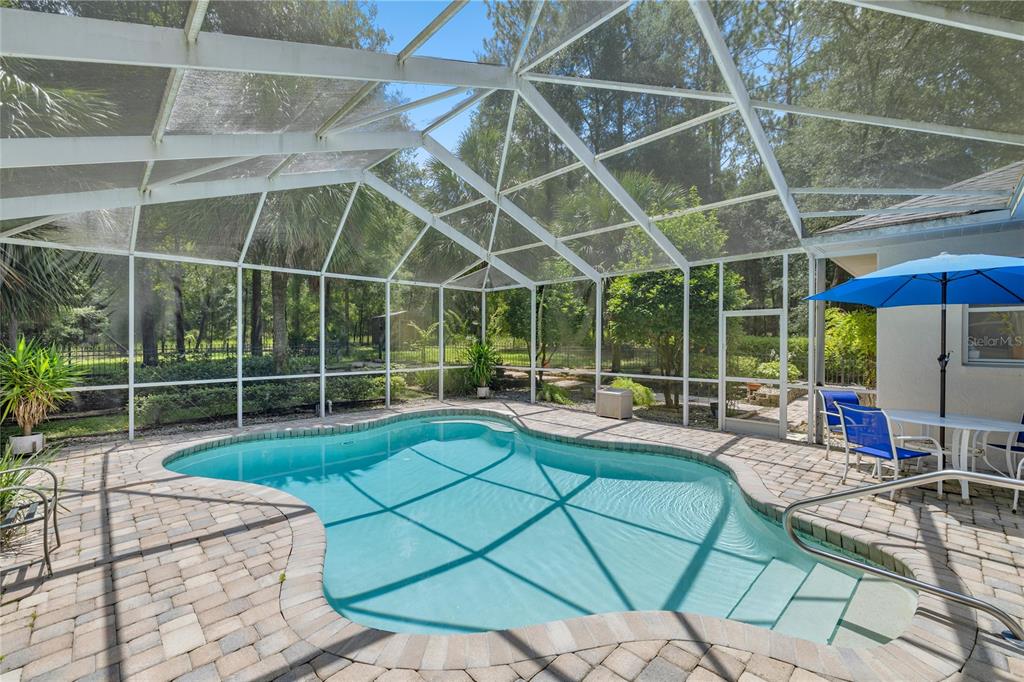 A screened-in swimming pool with a brick paver deck and patio furniture — 18293 SW 75TH LOOP, DUNNELLON, FL
