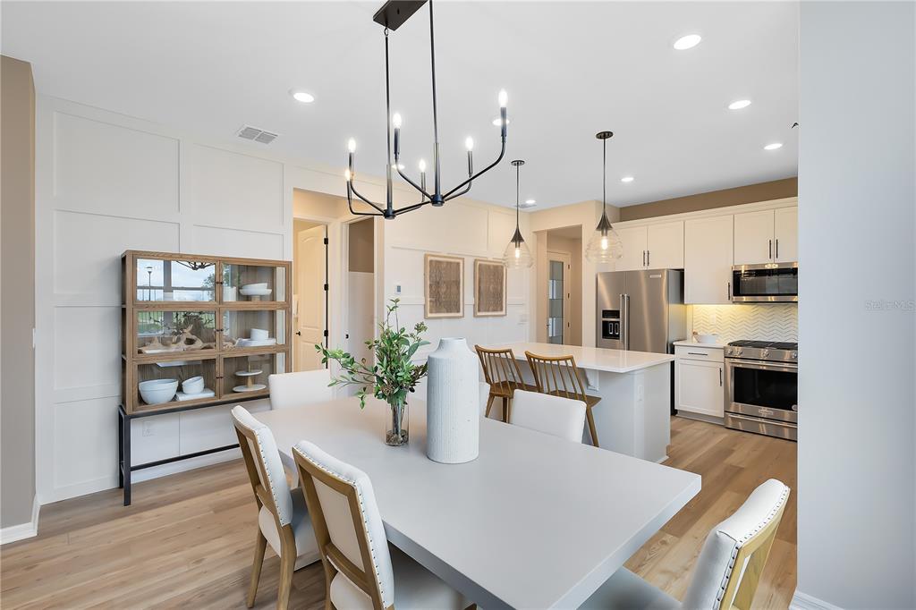 A dining area with a grey table and chairs sits adjacent to a modern kitchen — 2841 MIDSWEET AVENUE, ST CLOUD, FL