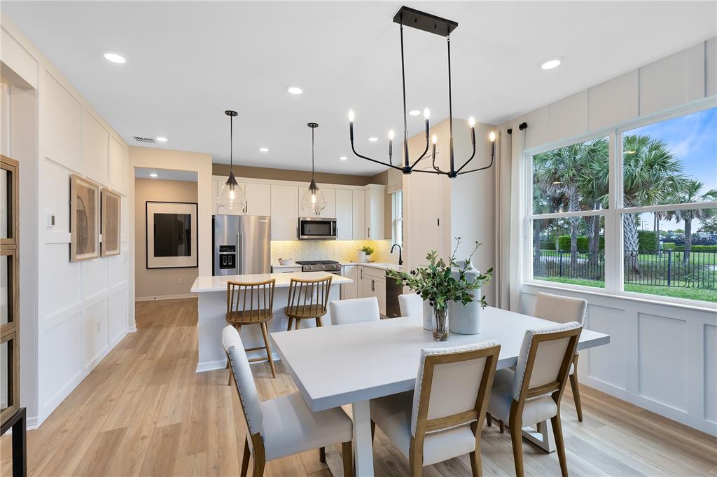 A dining area and kitchen feature white cabinetry, a central island, and light wood flooring — 2841 MIDSWEET AVENUE, ST CLOUD, FL