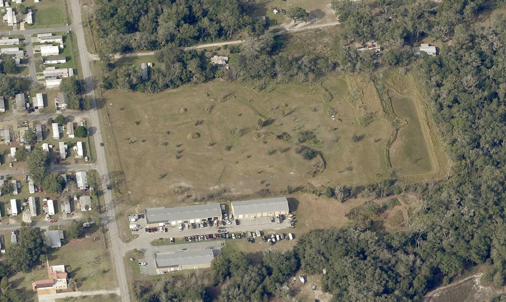 An aerial view shows a large grassy lot adjacent to commercial buildings and residential homes — 00 SE 102 PLACE, BELLEVIEW, FL