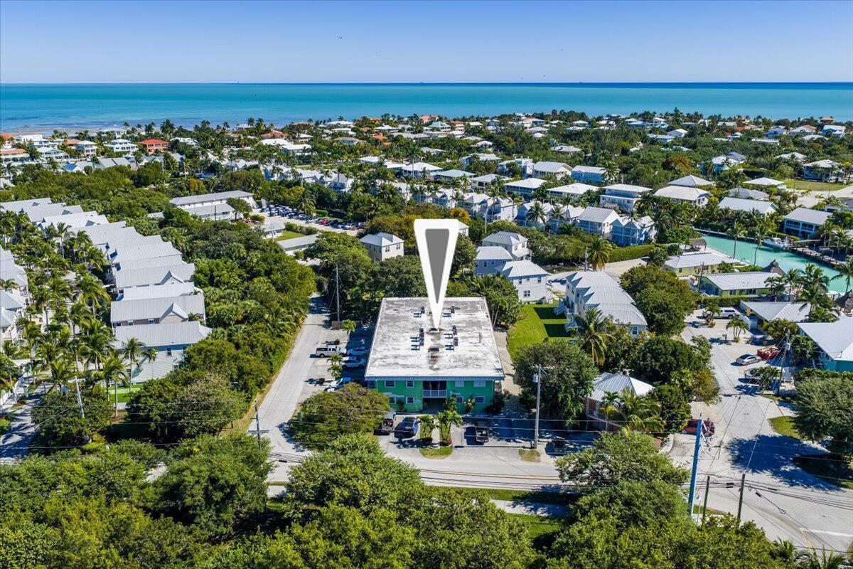 An aerial view shows a green multi-story apartment building surrounded by trees and residential homes — 1129 Pebble Beach Lane # 12, FL 33050, FL