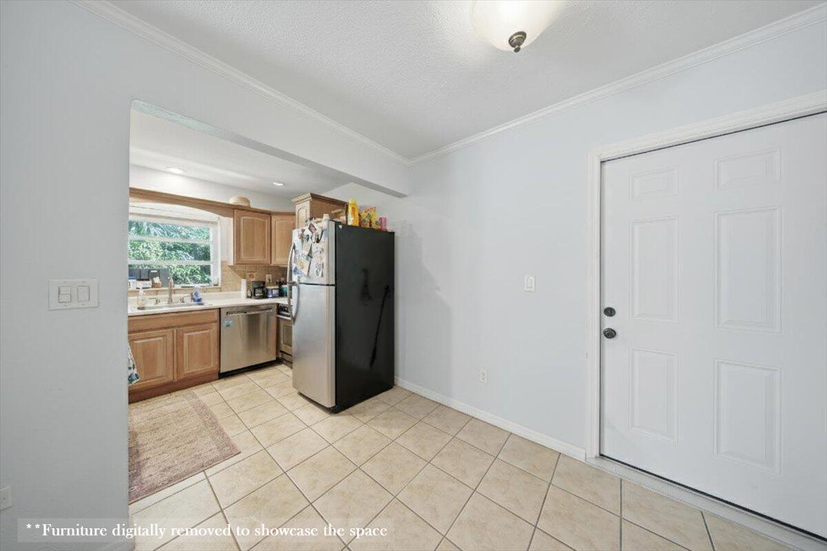 A kitchen with wood cabinets and a black refrigerator opens into a tiled dining area — 1129 Pebble Beach Lane # 12, FL 33050, FL