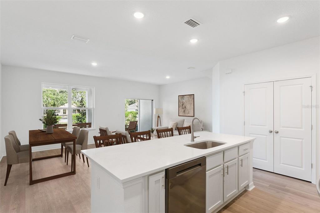 A kitchen island with a stainless steel dishwasher faces a dining area and living room — 2294 RED PINE COURT, EUSTIS, FL