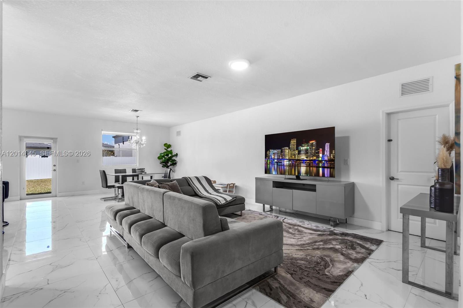 A living room features a gray sectional sofa, a television on a console, and white tile flooring — 13629 SW 186th Ln, Miami FL 33177, MIAMI, FL
