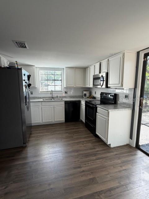 A kitchen features white cabinets, stainless steel appliances, and wood-look flooring — 9101 MONTEVELLO DRIVE, ORLANDO, FL