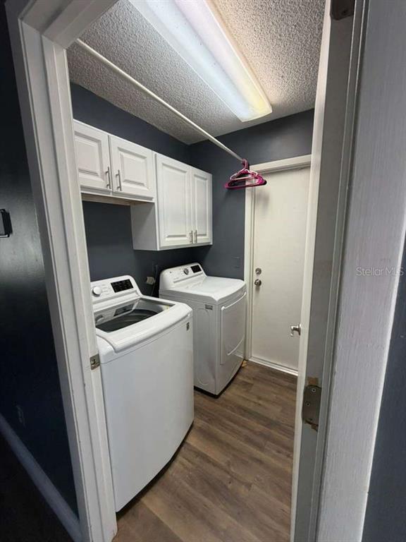 A laundry room with white appliances, white cabinets, and dark walls over wood-look flooring — 9101 MONTEVELLO DRIVE, ORLANDO, FL