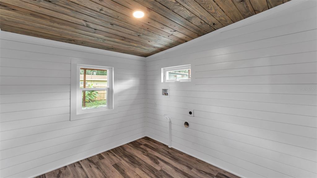 A laundry room features white shiplap walls, a wood-plank ceiling, and wood-look flooring — 127 COLONIAL DRIVE, AUBURNDALE, FL
