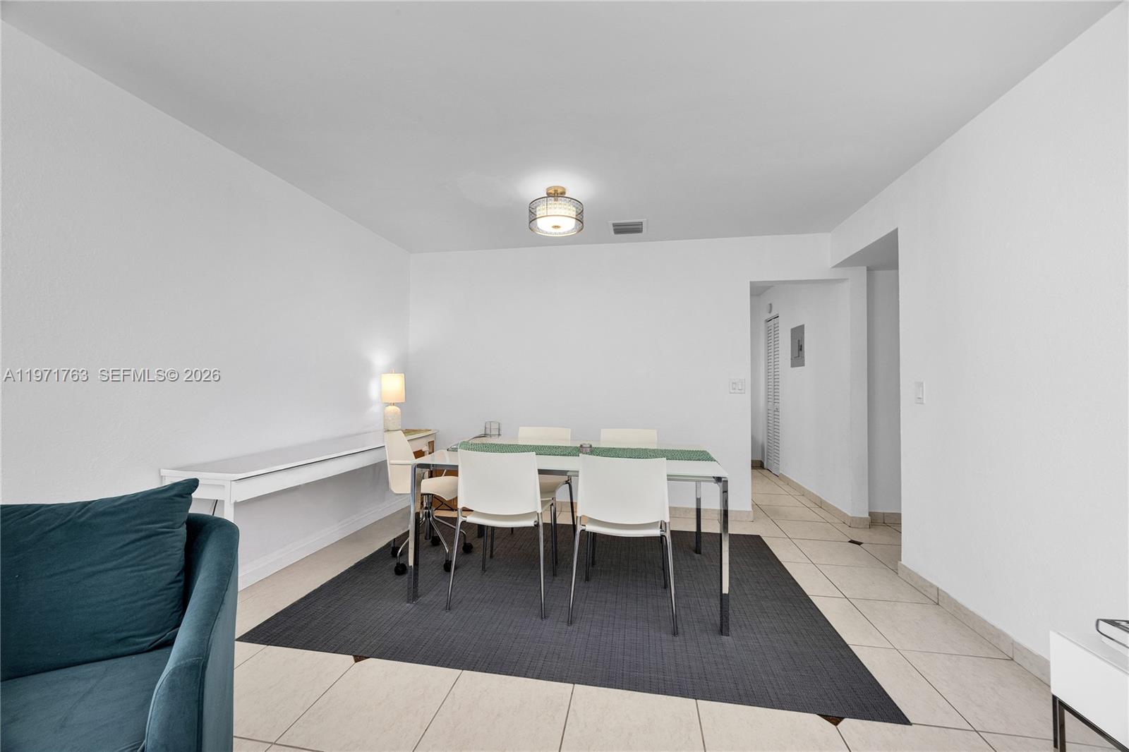 A dining area features a glass table, white chairs, and a dark rug on tile — 7785 SW 86th St # 414, Miami FL 33143, MIAMI, FL