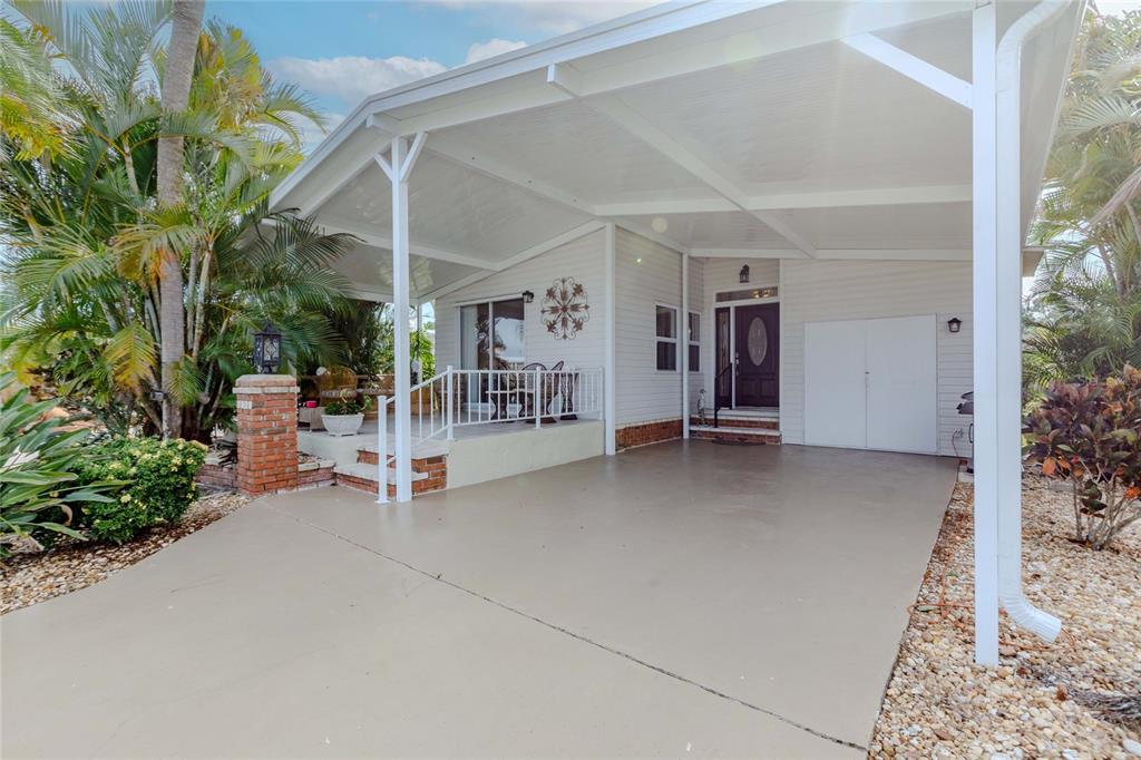 A covered patio features tiled flooring, wicker furniture, and a decorative wall ornament — 2100 KINGS HIGHWAY UNIT 1008, PORT CHARLOTTE, FL