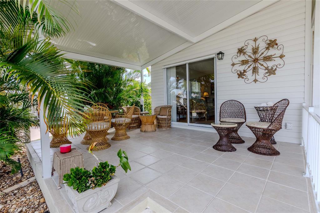 A covered patio features a glass-topped wicker dining set surrounded by potted palm plants — 2100 KINGS HIGHWAY UNIT 1008, PORT CHARLOTTE, FL
