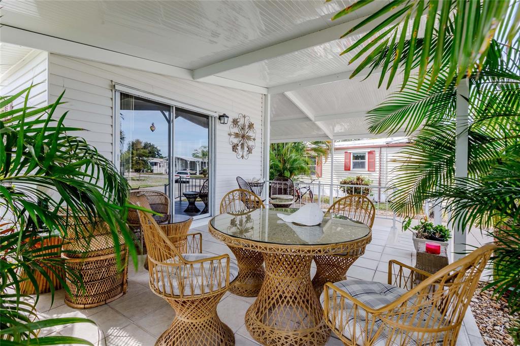 A living room features wood-look flooring, plaid sofas, a recliner, and a sliding glass door — 2100 KINGS HIGHWAY UNIT 1008, PORT CHARLOTTE, FL