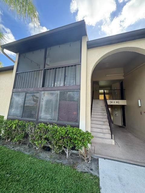 An exterior view of a two-story building with a screened balcony and concrete stairs — 628 N Sea Pine Way # A2, FL 33415, FL