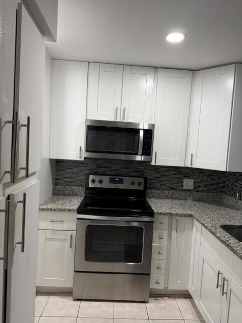 A kitchen features white cabinets, stainless steel appliances, and a dark tiled backsplash — 628 N Sea Pine Way # A2, FL 33415, FL