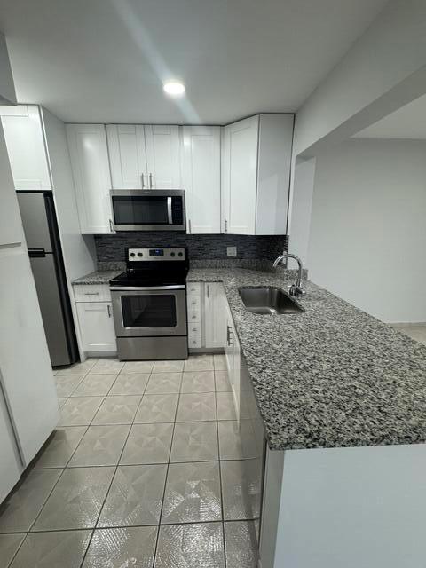 A kitchen features white cabinets, stainless steel appliances, and granite countertops over tiled floors — 628 N Sea Pine Way # A2, FL 33415, FL