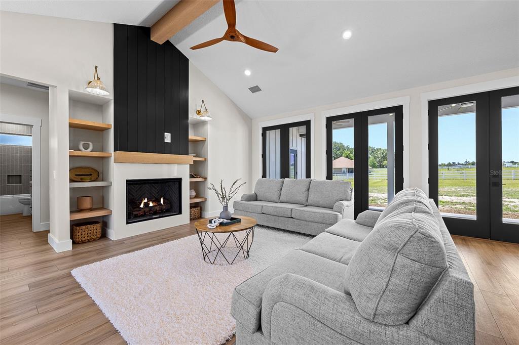 A living room features a fireplace with black paneling, wood shelving, and two grey sofas — 389 SW MOSSY OAK WAY, LAKE CITY, FL
