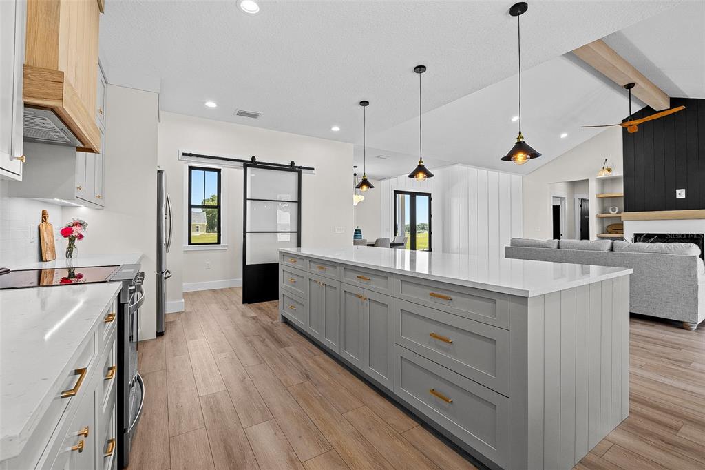 A modern kitchen features a large gray island, white countertops, and a sliding barn door — 389 SW MOSSY OAK WAY, LAKE CITY, FL