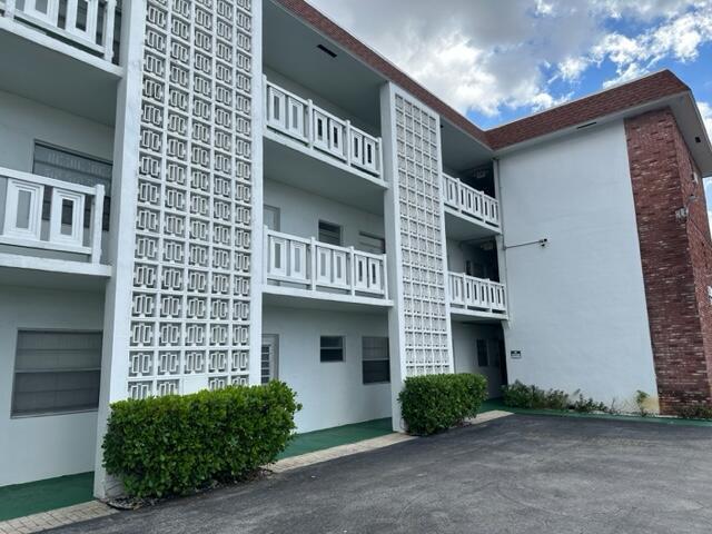A three-story apartment building features white walls, decorative concrete screen blocks, and brick siding — 1380 NW 43 Terrace # 306, Lauderhill FL 33313, LAUDERHILL, FL
