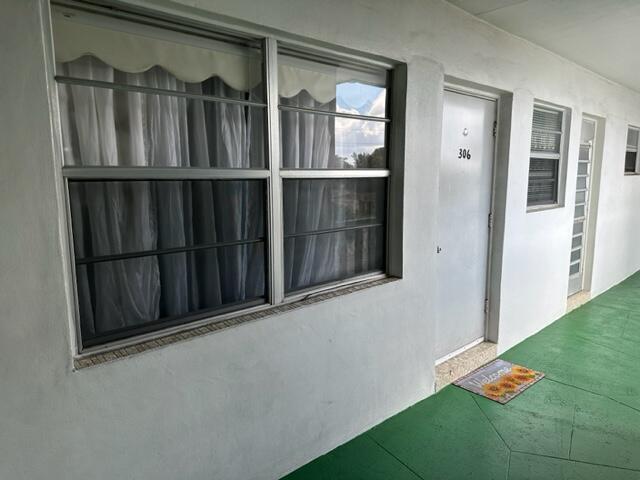 An exterior view of a building hallway with a window, a door numbered 306, and a doormat — 1380 NW 43 Terrace # 306, Lauderhill FL 33313, LAUDERHILL, FL