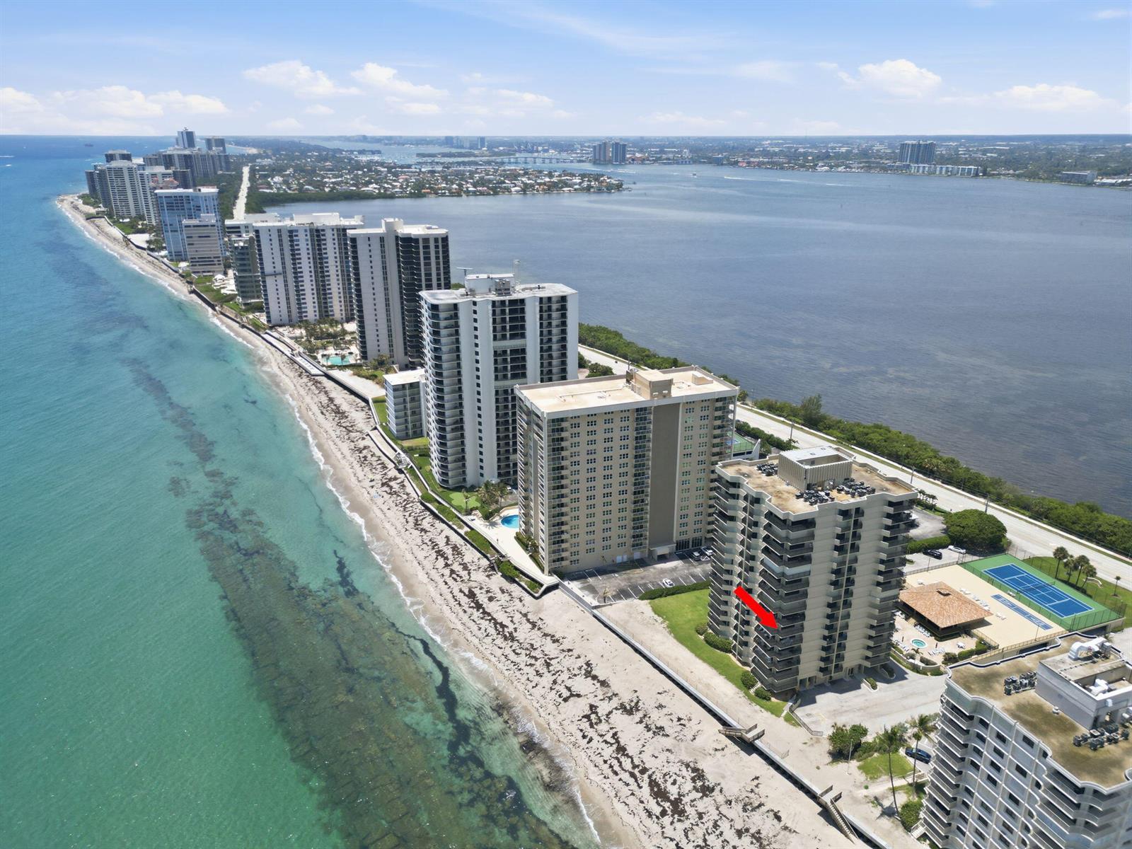 An aerial view shows a high-rise condominium building on a beach with a red arrow — 5460 N Ocean Drive # 6a, Riviera Beach FL 33404, RIVIERA BEACH, FL