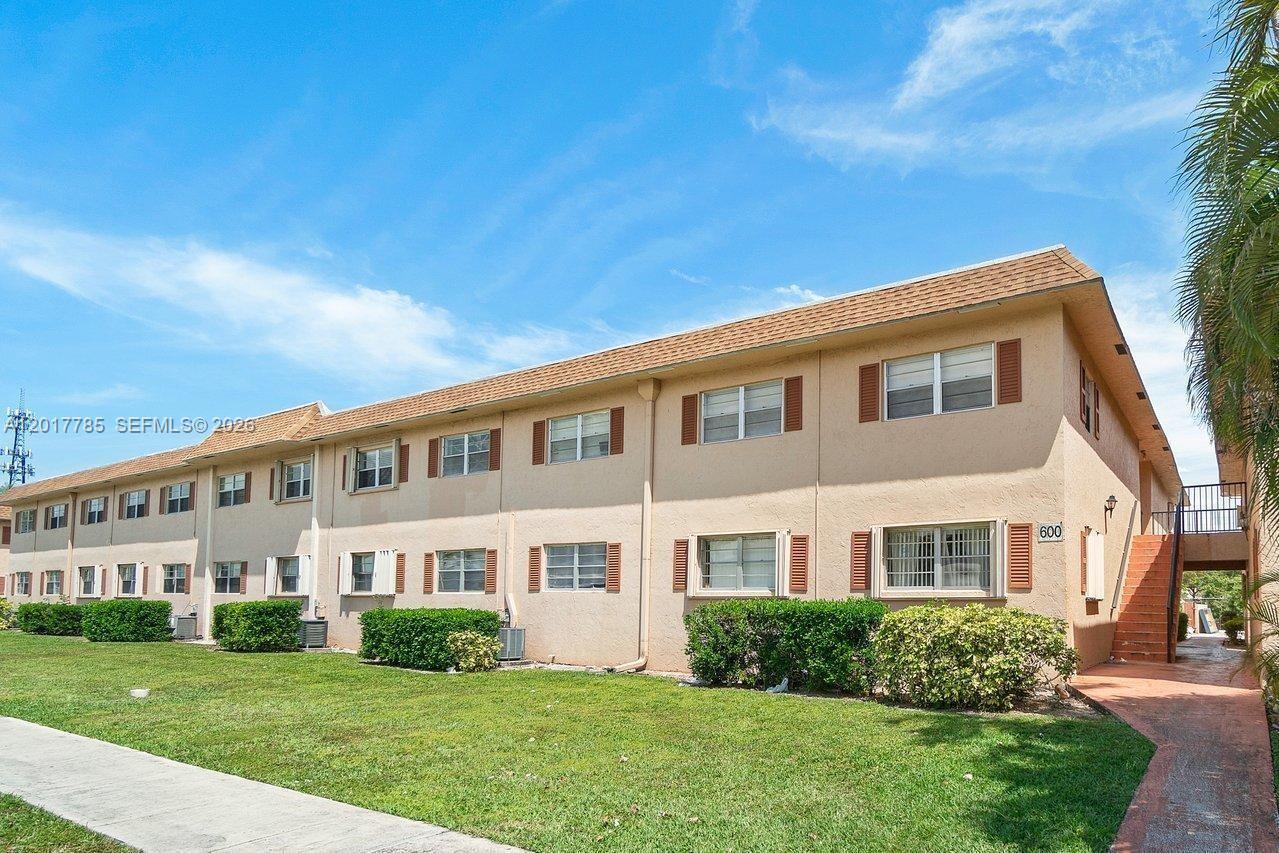 A two-story apartment building with tan stucco walls, brown shutters, and a grassy lawn — 500 SW 2nd Ave # 2150, Boca Raton FL 33432, BOCA RATON, FL