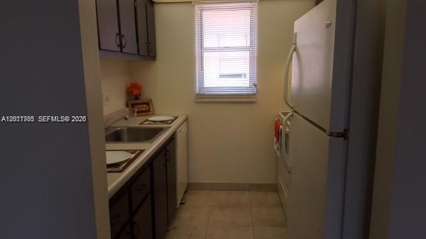 A galley-style kitchen features dark cabinets, a white refrigerator, a sink, and tiled flooring — 500 SW 2nd Ave # 2150, Boca Raton FL 33432, BOCA RATON, FL