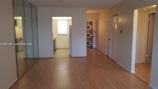 An interior view of a room with light wood flooring, mirrored walls, and a kitchen doorway — 500 SW 2nd Ave # 2150, Boca Raton FL 33432, BOCA RATON, FL