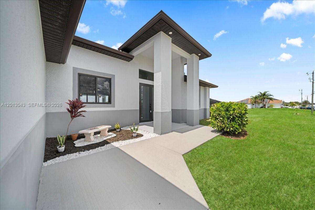 The exterior of a modern house features a concrete walkway leading to a covered entryway — 1925 NW 15TH TER, Cape Coral FL 33993, CAPE CORAL, FL