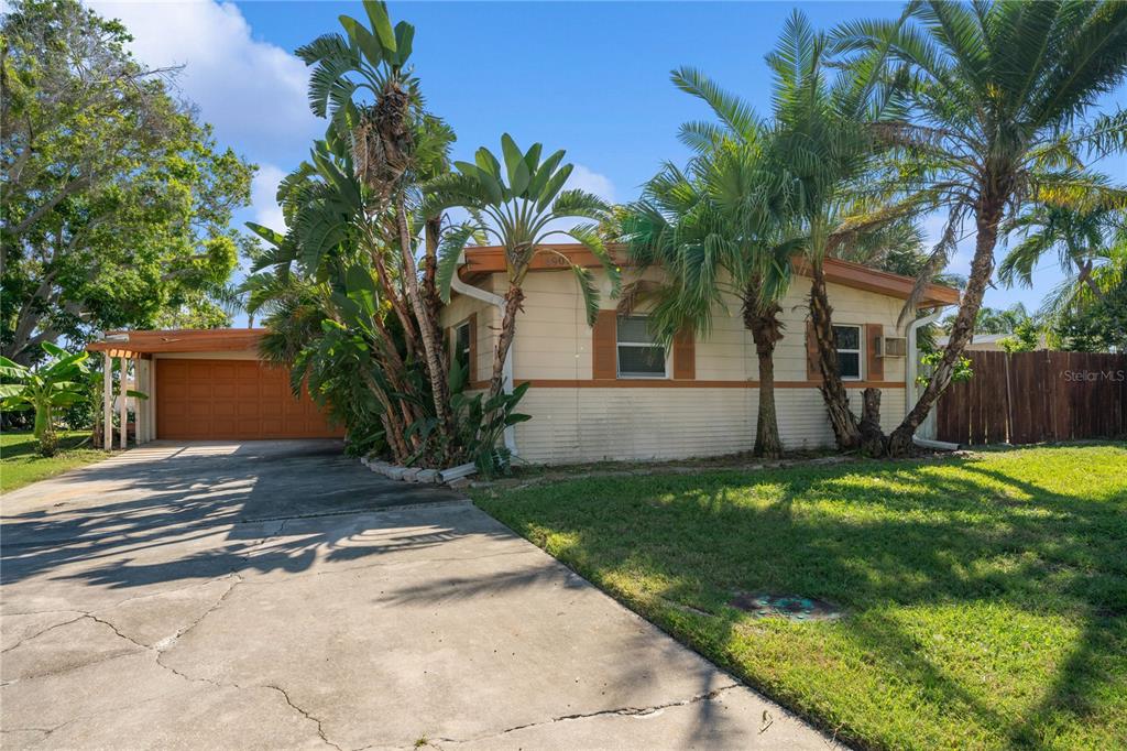 A single-story house with a beige exterior, a carport, and palm trees in the front yard — 6903 S SHORE DRIVE S, SOUTH PASADENA, FL
