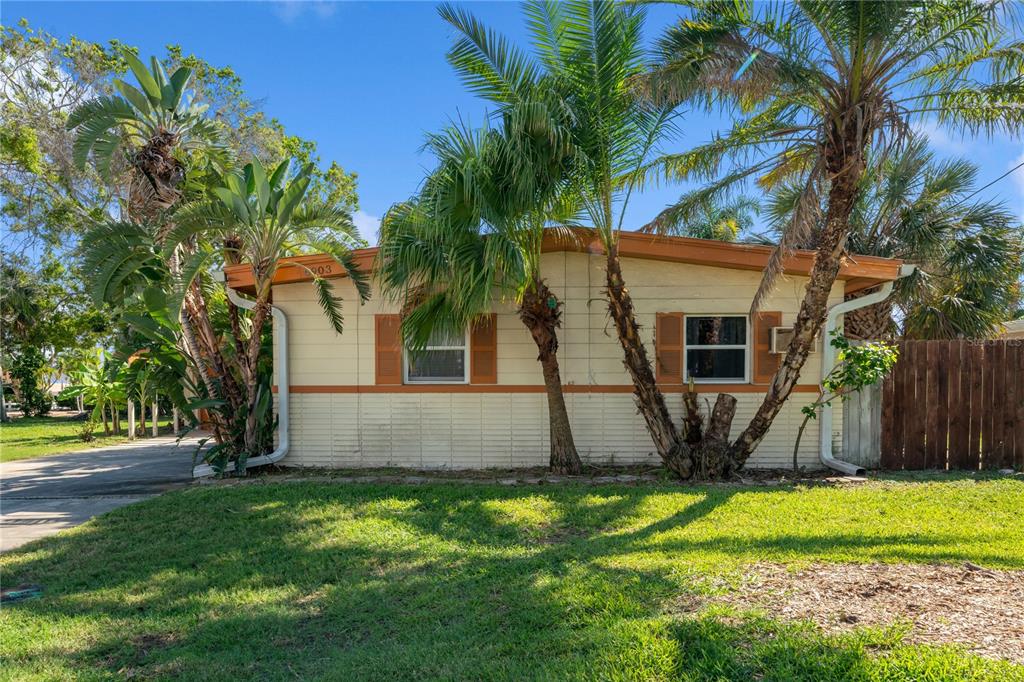 A single-story house with light-colored siding, brown shutters, and palm trees in the front yard — 6903 S SHORE DRIVE S, SOUTH PASADENA, FL