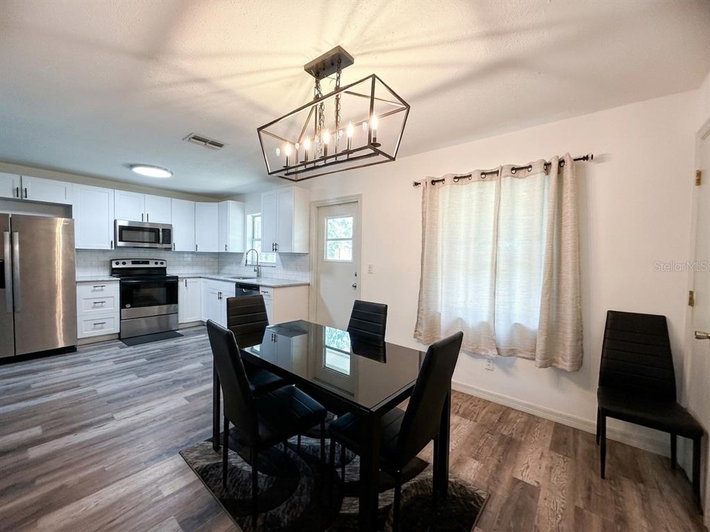 A kitchen and dining area with white cabinets, stainless steel appliances, and a black table — 636 RAINBOW BOULEVARD, BABSON PARK, FL