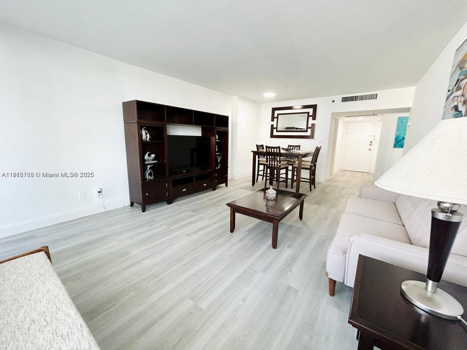 A living and dining area features light wood-look flooring, dark furniture, and white walls — 100 Lincoln Rd # 535, Miami Beach FL 33139, MIAMI BEACH, FL
