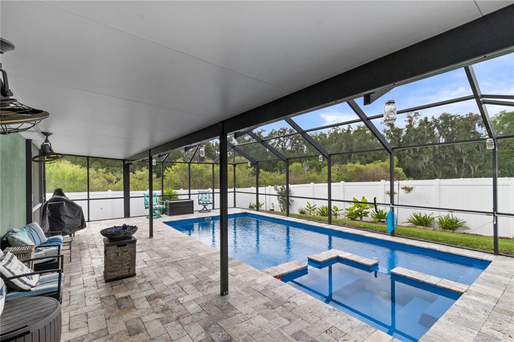 A screened-in swimming pool and patio area with a tiled deck and white privacy fence — 4562 FAIRWAY OAKS DRIVE, MULBERRY, FL