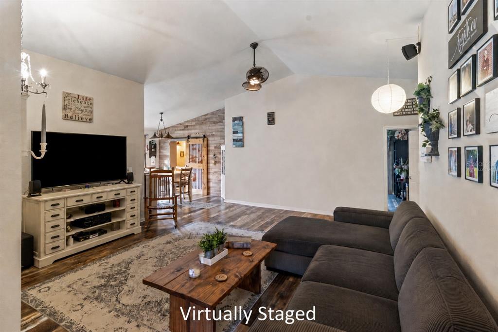 A living room features a sectional sofa, wooden coffee table, television console, and vaulted ceilings — 4562 FAIRWAY OAKS DRIVE, MULBERRY, FL