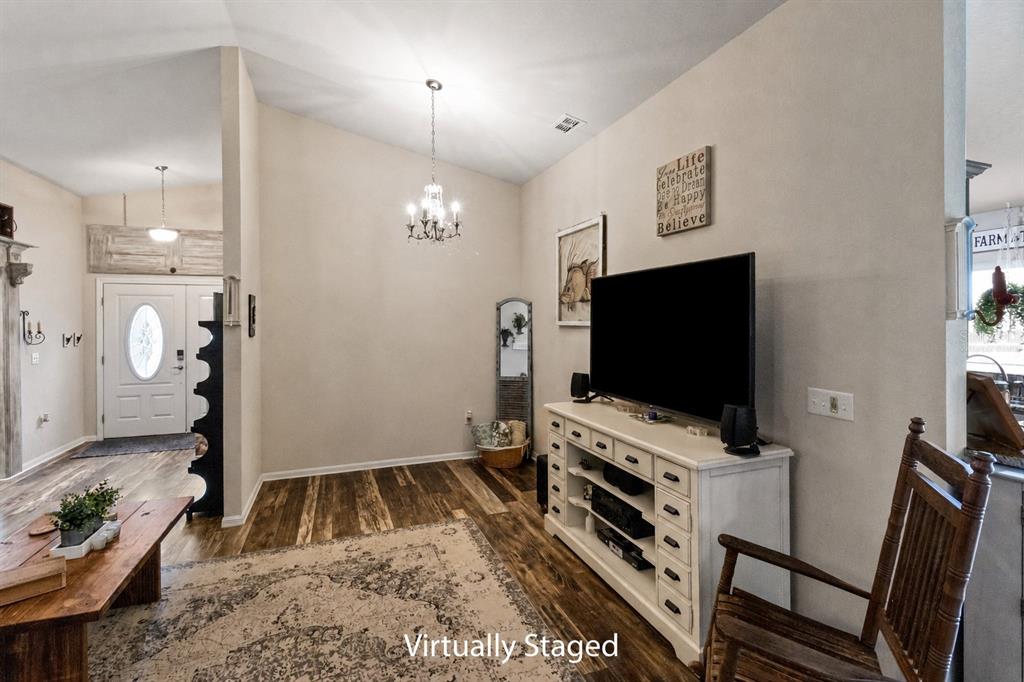 A living room features a television on a white console, a chandelier, and wood flooring — 4562 FAIRWAY OAKS DRIVE, MULBERRY, FL