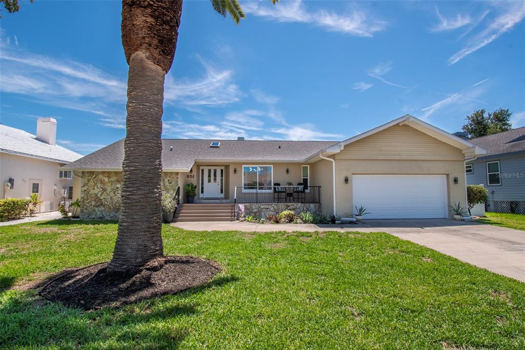 A single-story house with a stone facade, a palm tree, and a two-car garage — 851 3RD AVENUE S, TIERRA VERDE, FL
