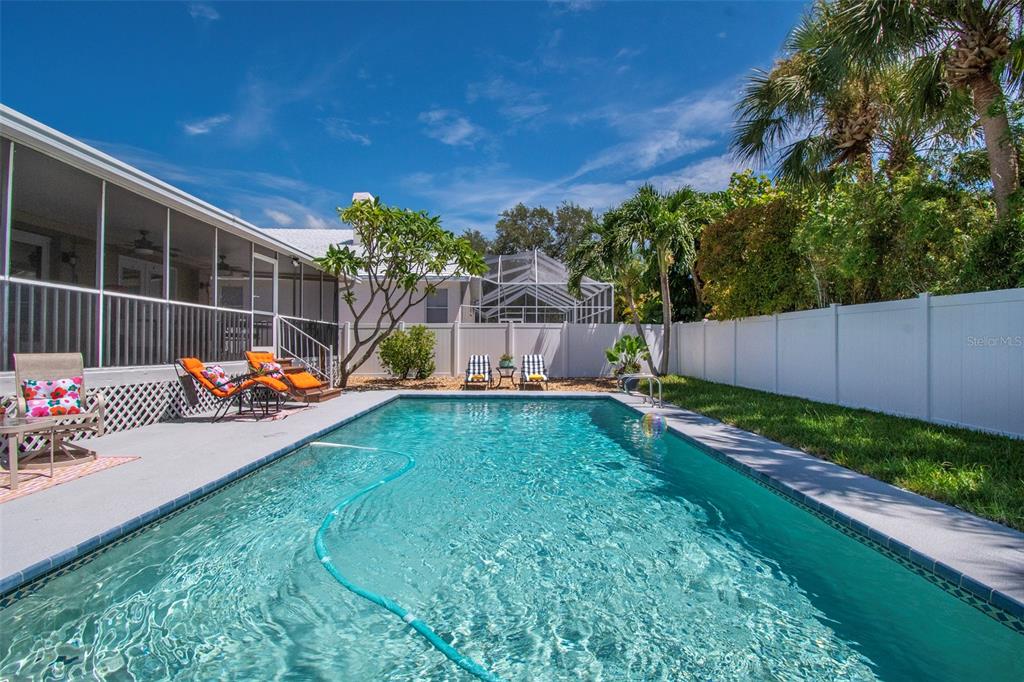 A rectangular swimming pool sits in a backyard with a white fence and patio furniture — 851 3RD AVENUE S, TIERRA VERDE, FL