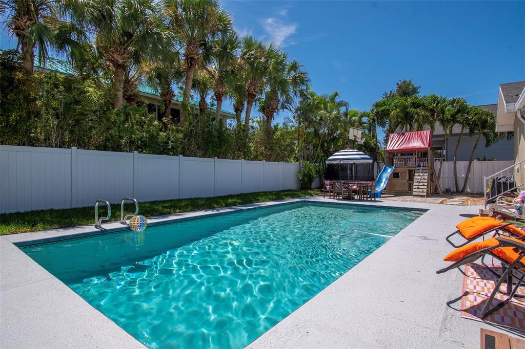 A rectangular swimming pool with a white fence and palm trees in a backyard — 851 3RD AVENUE S, TIERRA VERDE, FL